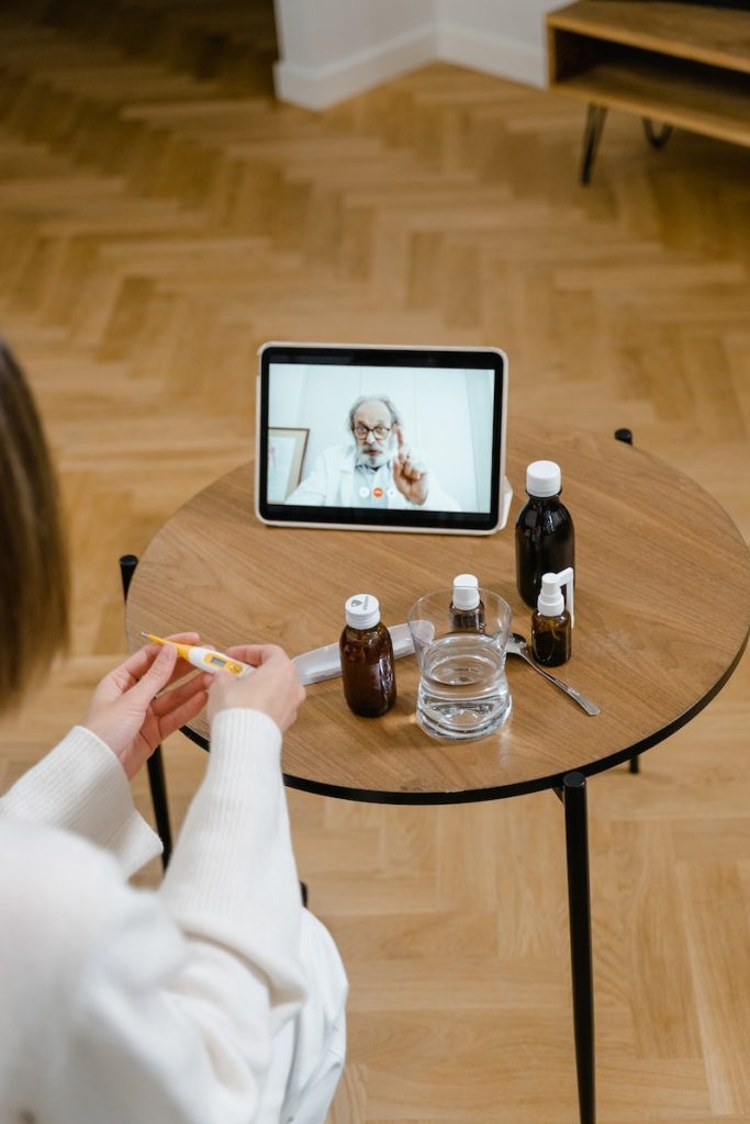 Woman in White Long Sleeve Shirt Sitting on Chair in Front of Table With Digital Tablet